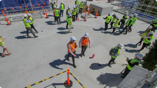 Construction site personnel wearing essential personal protective equipment (PPE), including hard hats and reflective safety vests.