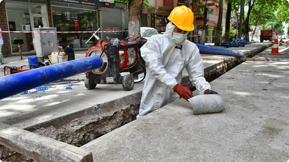 Worker in protective suit and hard hat handling materials safely to avoid asbestos exposure on a construction site.