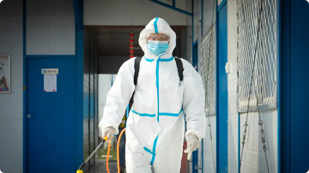 Professional in a full protective suit and mask carrying out asbestos inspection and decontamination work.